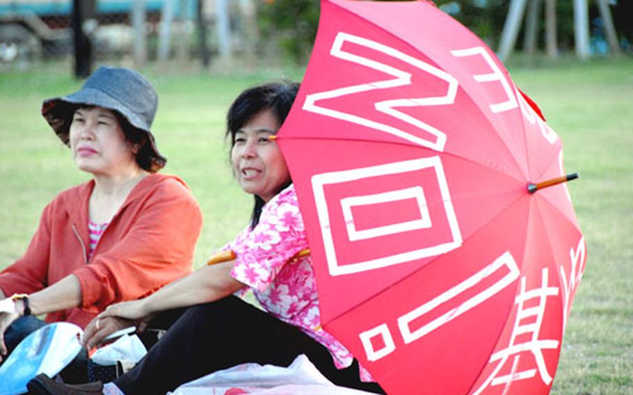 Some rally-goers showed up Wednesday with red umbrellas embellished with slogans such as "No Base" and "No War. Peace."