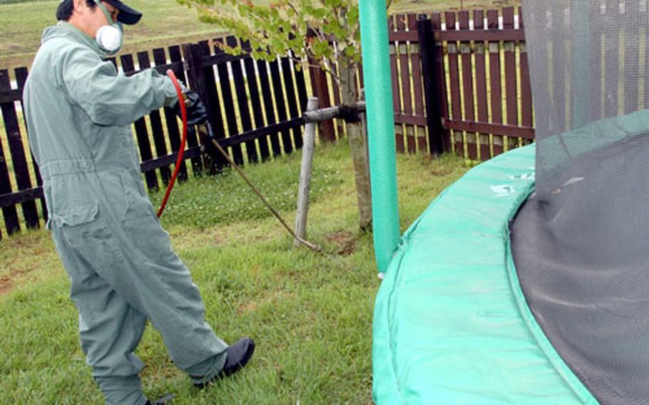 Kunimitsu Kawasaki, a pest controller at Misawa Air Base, sprays a trampoline for spiders in main-base housing this week.