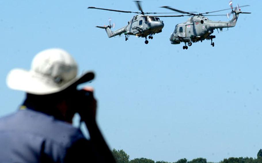 A photographer snaps a shot of two Lynx helicopters from the Royal Navy displaying their skills.