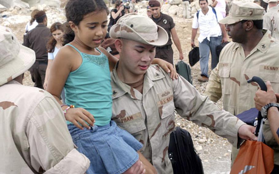Petty Officer 3rd Class Giang Pham from Beachmaster Unit 2 carries a girl to a U.S. Navy landing craft that will shuttle her and other evacuees to a ship bound for Cyprus.