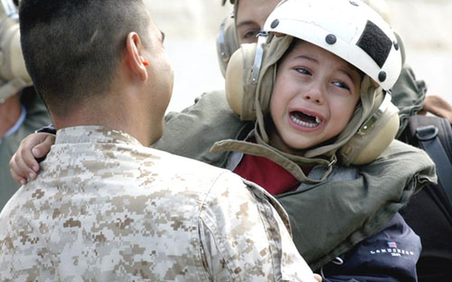 Capt. Pablo Cabrera, 1st Battalion, 8th Marines, attached to the 24th Marine Expeditionary Unit, carries a boy toward a U.S. Marine helicopter at the U.S. Embassy in Beirut.