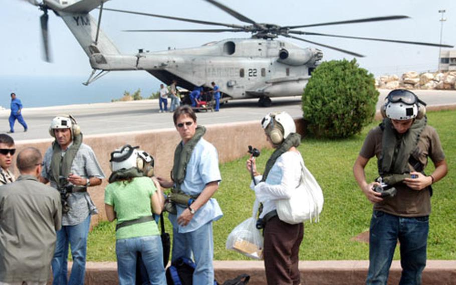 U.S. citizens waiting to be evacuated to Cyprus from the U.S. Embassy in Beirut inspect the safety gear given to them by Marines standing by to fly them out by helicopter on Friday.