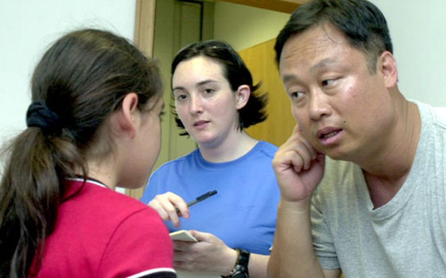 Air Force Capt. Chi Suh, a nurse from Landstuhl Regional Medical Center in Germany, questions Ruba Kalakech, 9, of Beirut, Lebanon, as Air Force Staff Sgt. Tanya Ayon observes Friday at the Cyprus International Fairgrounds in Nicosia, Cyprus.