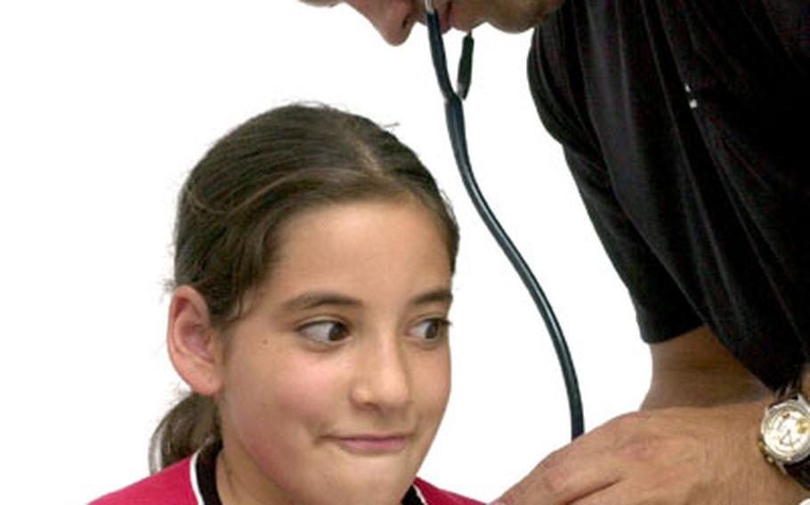 Air Force Capt. Justin Cummings, a doctor of internal medicine from Landstuhl Regional Medical Center in Germany, examines Ruba Kalakech on Friday at the Cyprus International Fairgrounds in Nicosia, Cyprus. Cummings is attached to the 435th Medical Group at Ramstein Air Base.