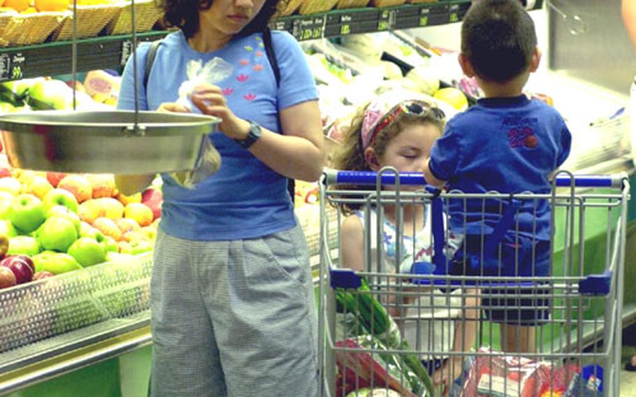 Kim Martin, of South Korea, browses the fruit and vegetable section at the Vilseck, Germany, commissary with her children Rachel, 6, and David, 3.
