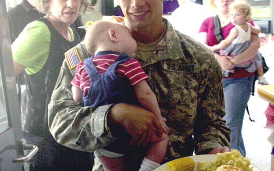 Company A, 1st Military Intelligence Battalion soldier Spc. Ben Smith, 25, carries his 3-month-old son, Hunter, who was born while his father was downrange, at a welcome home party Friday for the unit at Hohenfels, Germany.