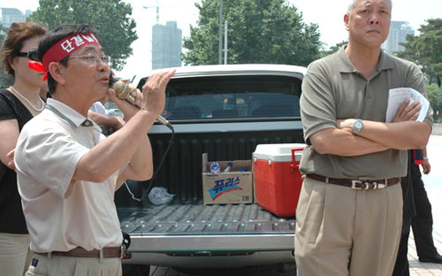 Bae Sam-jin, an Arirang taxi driver for 15 years, tries to calm more than 100 protesting drivers Saturday afternoon after hearing from AAFES Pacific Services Manager Cliff Choy, right, that AAFES can bar the drivers from current and future employment on any contracts with the exchange service.