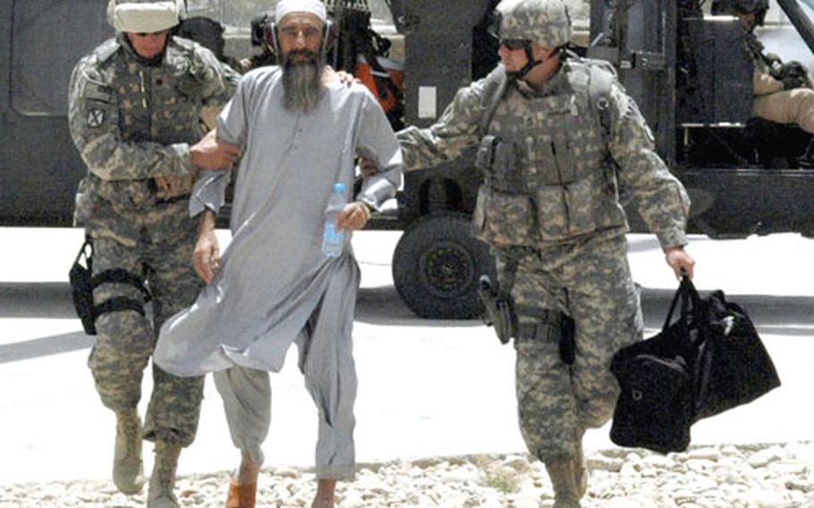 U.S. soldiers escort Rias Mullah Abdul Ali Akundzada out of a helicopter and onto the provincial reconstruction team headquarters in Qalat, Afghanistan. Akundzada was detained by U.S. forces for aiding the Taliban, but released Sunday at the request of other religious leaders from his district.