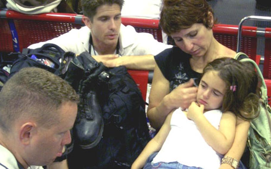 Air Force Capt. (Dr.) Derrick Darnsteadt, rear, and Tech. Sgt. Nathan Leeman, foreground, assist an evacuee and her child at a processing center in Cyprus last week.