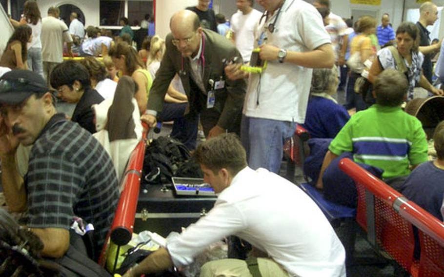 Dr. Richard Nicholas, leaning forward, a State Department medical officer from Cairo, Egypt, checks medical gear with Air Force medics Tech. Sgt. Nathan Leeman, right, and Capt. (Dr.) Derrick Darnsteadt, crouched, at an evacuation center.