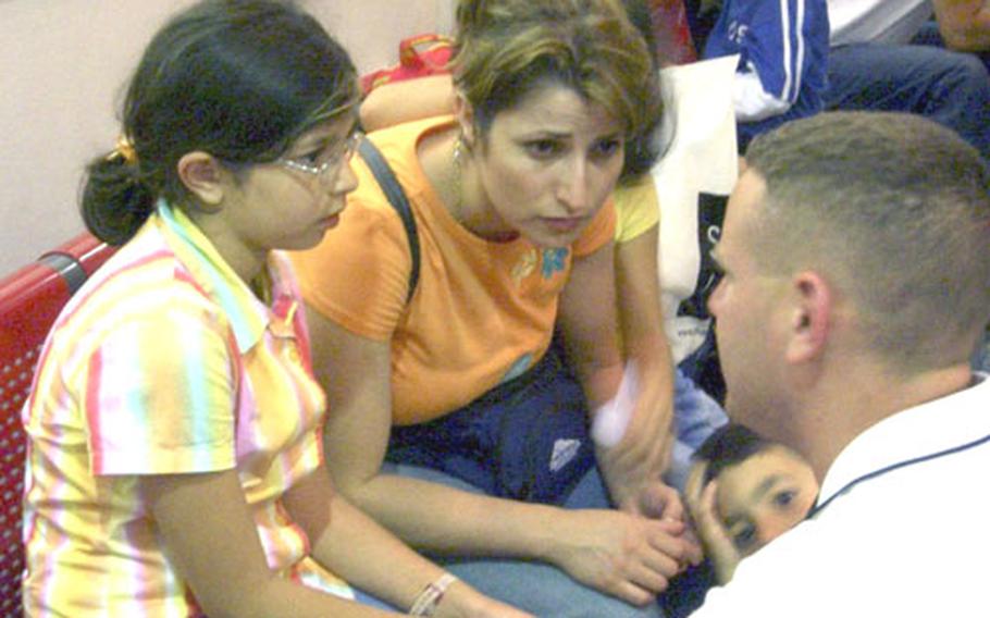 Air Force medic Tech. Sgt. Nathan Leeman consults with a family at an evacuation center in Cyprus last week.