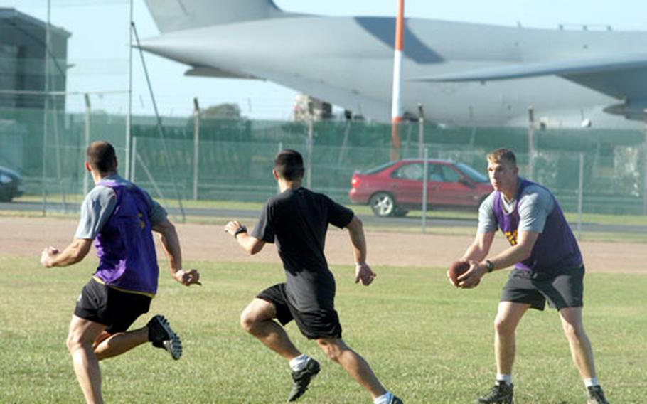 Three airmen play rugby at Ford Field as part of their physical training.