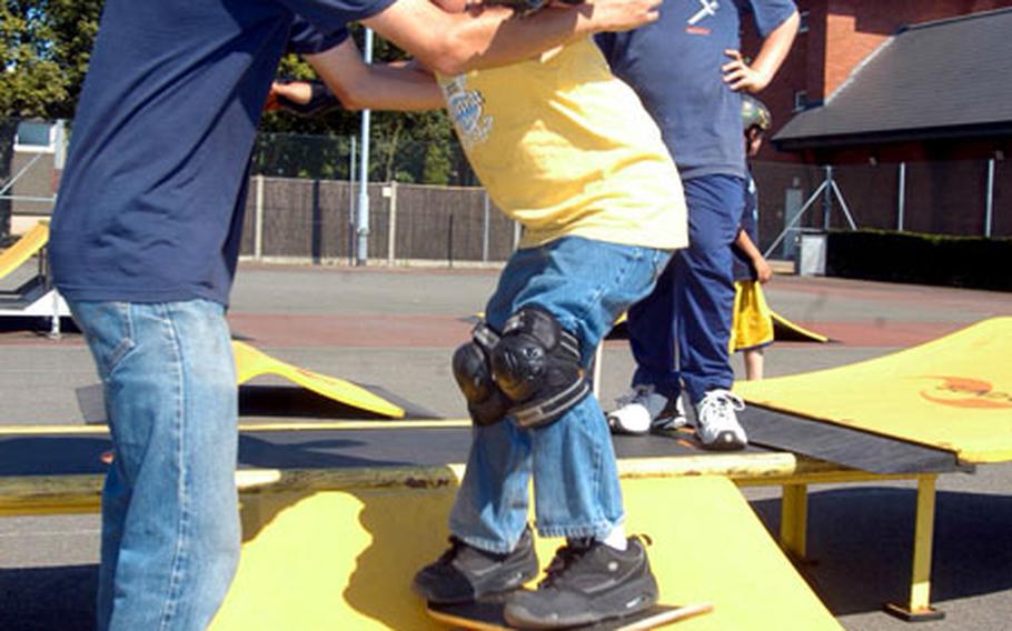 Instructor Bill Welk assists 8-year-old Nathan Reyes as he practices dropping in from a ramp.