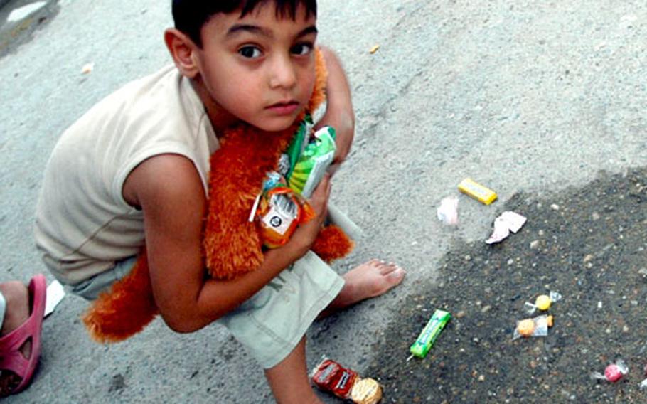An Iraqi boy scoops up toys and candy handed out by Marines during a civil engagement mission in Fallujah.