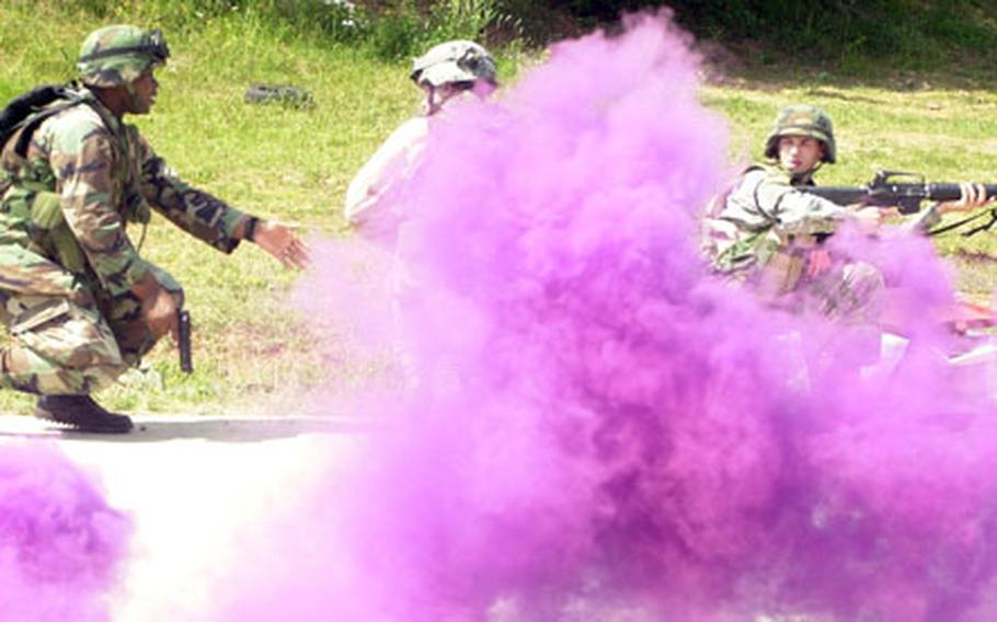 Concealed by a smoke grenade, an officer urges on soldiers during training at Baumholder.