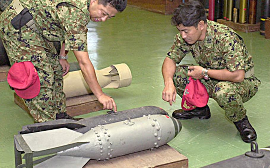 Sgt. 1st Class Tsutomu Matsui and Lt. Col. Keizo Zagaya, both with the Japanese Self-Defense Force, examine an old-style Japanese bomb Tuesday at the Explosive Ordnance Disposal Company museum on Camp Hansen. The museum, which the company uses as a training tool, contains ordnance from around the world.