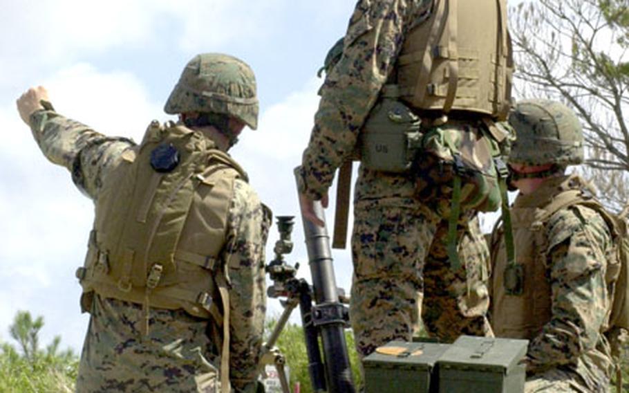 Cpl. Donald Ferreira, 22, of Jacksonville, Fla., the team leader for Gun 1, points out an impact downrange for Lance Cpl. Carter Bossow, 21, of Spencer, Iowa, and Pfc. Shuan Garvey, 19, of Indianapolis.