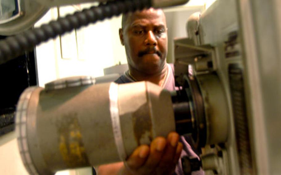 John Rhynes, a movie theater manager who has worked at Rammers Theater for more than six years, changes the lens on a projector Tuesday. The movie, "Pirates of the Caribbean: Dead Man&#39;s Chest," wasn&#39;t supposed to be shown at Babenhausen, but Rhynes showed the film as a treat for the community, which will see the theater close Friday.