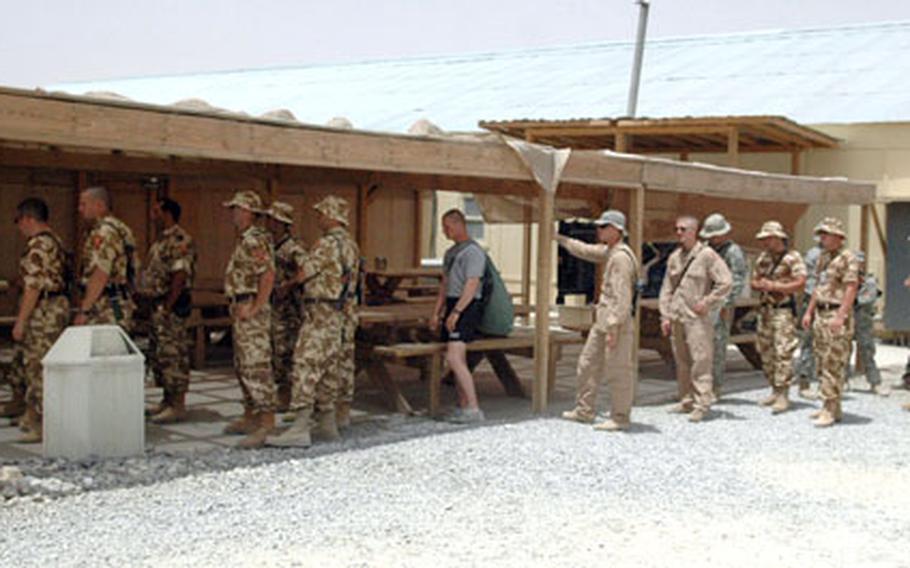 Romanian and U.S. soldiers line up outside of the dining hall at Forward Operating Base Lagman, Afghanistan, on Wednesday. NATO forces will soon take over major operations at this base and others from the soldiers of 2nd Battalion 4th Infantry Regiment, but for the next few weeks both sides will have to live with crowded conditions as the base absorbs several hundred new troops before the change-over.