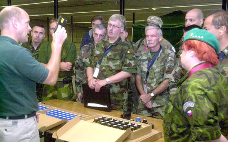 Eric Damm, U.S. European Command’s nonlethal weapons engagement officer, discusses the Taser with a crowd of military members from a variety of nations Wednesday during their Vienna Document visit to Rhine Ordnance Barracks in Kaiserslautern, Germany.