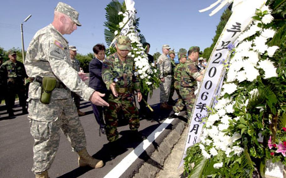 Command Sgt. Maj. Daniel P. Ciarrocchi, left, of the United Nations Command Security Battalion–Joint Security Area, assists in placing wreaths on a memorial for two U.S. soldiers killed in the JSA during an Aug. 18, 1976, attack. The security battalion hosted a memorial ceremony for the soldiers Friday.