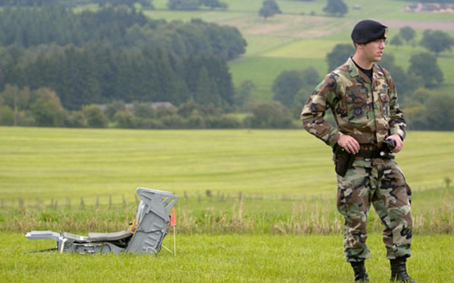 Airman Benjamin Martin, a security forces specialist assigned to the 52nd Security Forces Squadron, stands guard alongside the ejection seat from a Spangdalem Air Base F-16 that crashed Thursday.