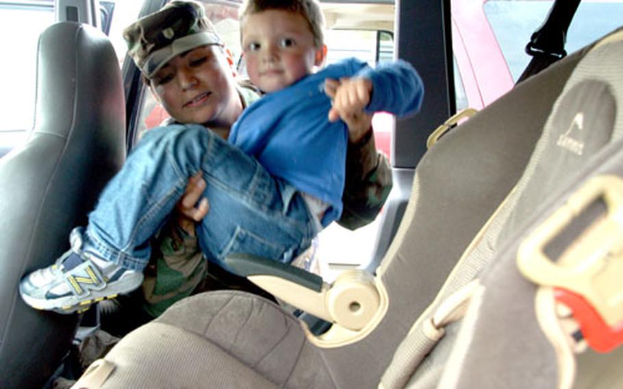 Staff Sgt. Valerie Smith loads her son, Gabriel, into his rear car seat.