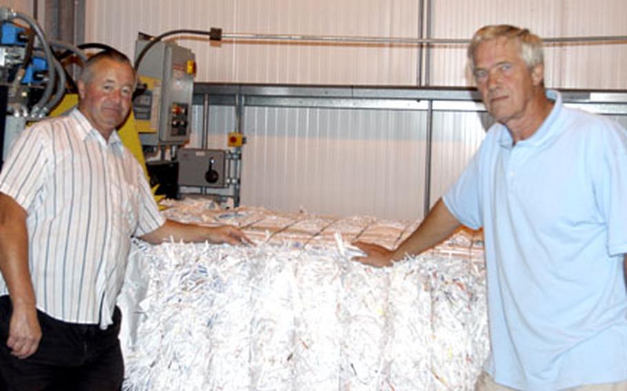 Brian Giles, left, and Rod Barrett, stand next to a bundle of shredded paper set to be recycled. The two British men work at the RAF Lakenheath recycling center as employees of the Ministry of Defence.