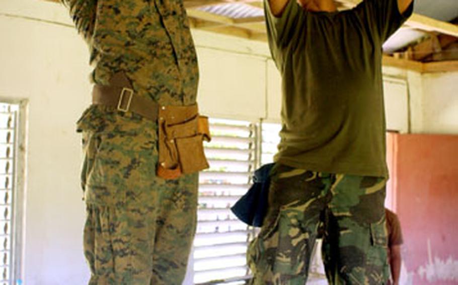 A U.S. Marine and a Philippine Seabee rebuild the roof of an elementary school in support of exercises Talon Vision and Amphibious LAnding Exercise FY ‘07.