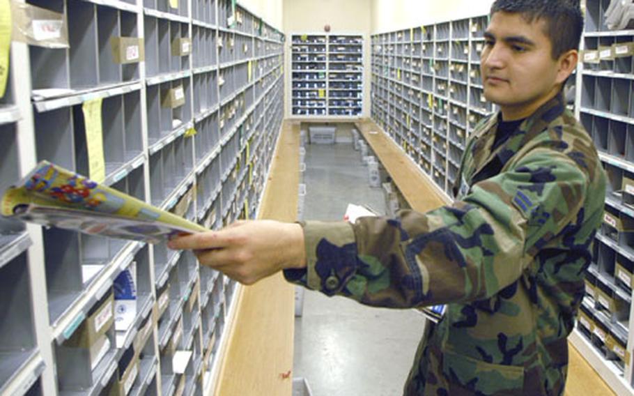Airman 1st Class Mario Carranza delivers mail to one of the boxes at RAF Mildenhall’s post office last week.