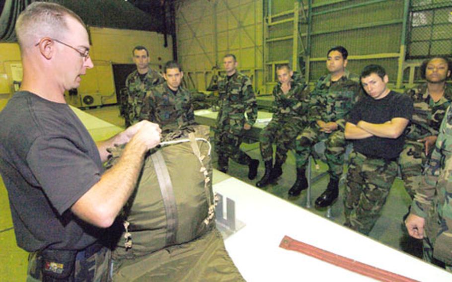 Inside a hangar bay on Yokota Air Base, Japan, last week, Tech. Sgt. Seth Abel instructs a class of airmen on how to package a parachute and what to look for when inspecting it.