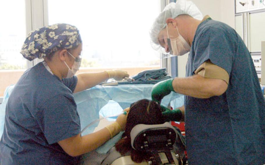 Petty Officer 3rd Class Dwan Pamaran and Lt. Cmdr. Richard Laing work on a patient at the new oral/maxillofacial surgery suite at the U.S. Naval Hospital Yokosuka, Japan, on Wednesday.