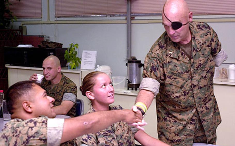 Clebe McClary, a Marine veteran who was severely wounded during the Vietnam War, shakes hands with Marines at the USO on Camp Hansen, Okinawa, on Friday.