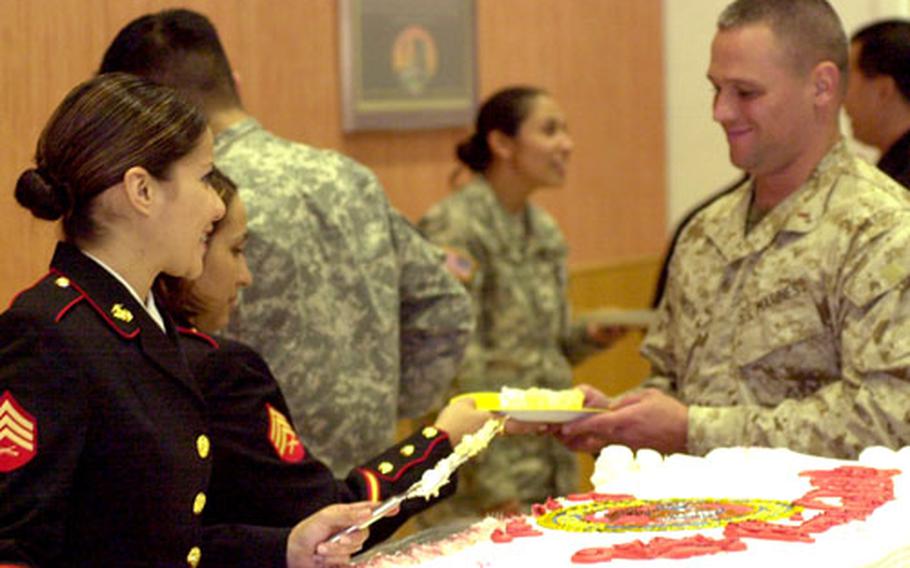 Marine Sgt. Rachel Rodriguez hands a piece of cake to Marine Chief Warrant Officer 2 William Lawson while Sgt. Nibya Contreras looks on.