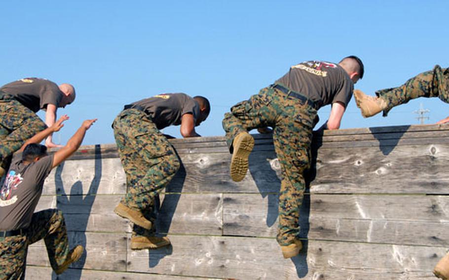 Members of team “Magic Stick” hurl themselves over the wall of the obstacle course Sunday. Most of the sailors of the team recently served together in Iraq with the Marine Corps 9th Engineer Support Battalion.