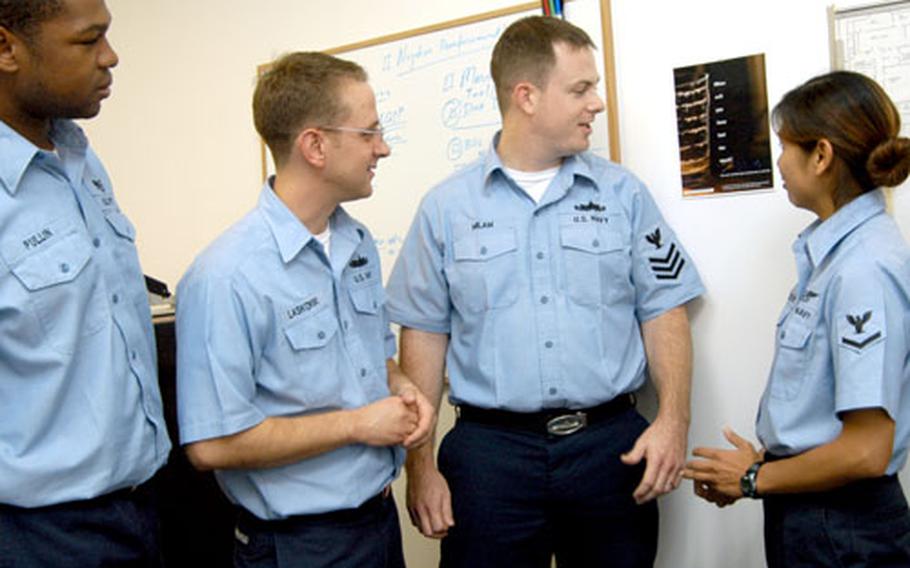 From left, Petty Officer 2nd Class Joshua Laskowsk, with colleagues Petty Officer 1st Class Michael Milam and Petty Officer 3rd Class Priscilla Nelson, put up a “None for the Road” poster last week at Yokosuka Naval Base, Japan.