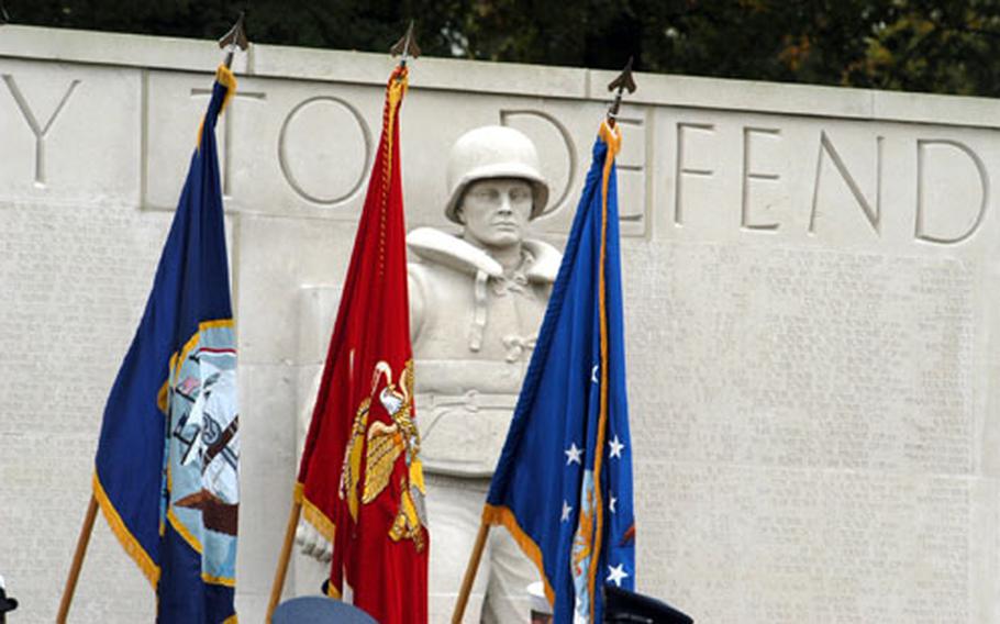 A statue of a sailor stares through the flags from the American and British military over the American Military Cemetery in Madingley during the annual Veterans Day ceremony.