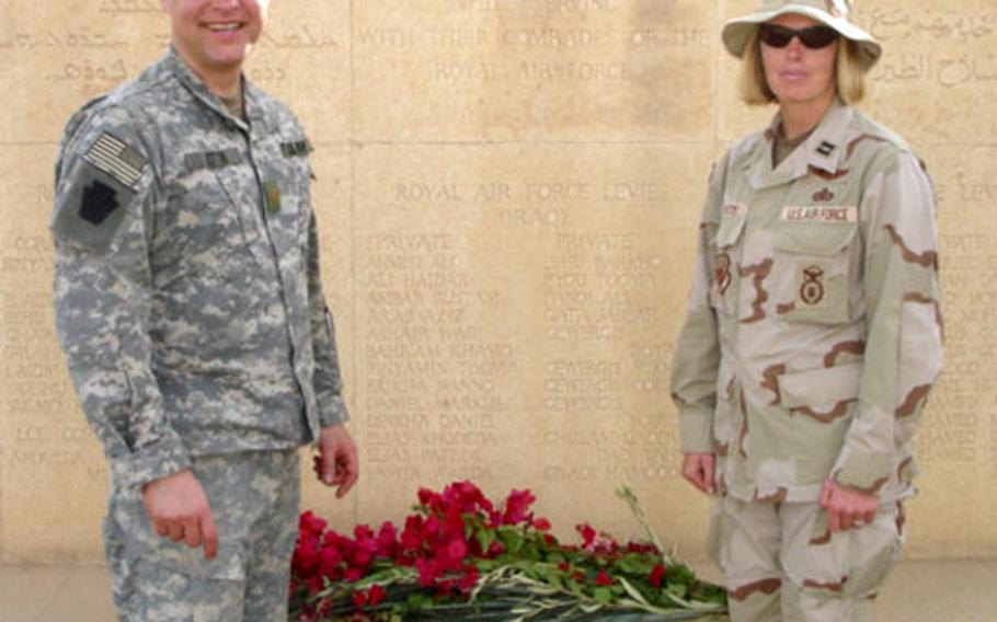 U.S. Air Force Capt. Jutta Cortes stands with another servicemember alongside the memorial wall at the RAF Habbaniyah Cemetery in Iraq.