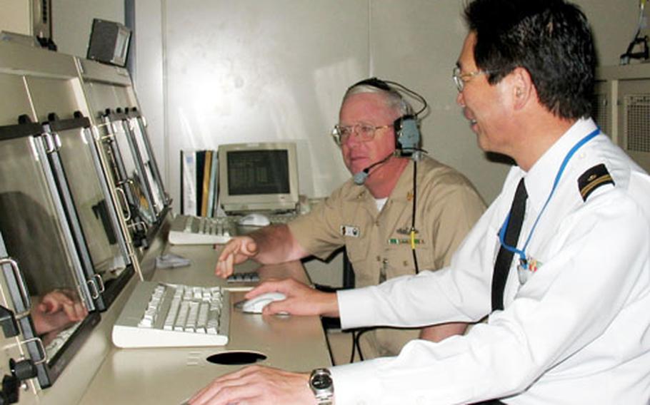 Lt. Hideo Nakako, Japan Maritime Self Defense Force Anti Submarine Warfare tactics officer in charge; and Senior Chief Petty Officer Wynn Sullivan of the Yokosuka detachment of the Navy's Center for Surface Combat Systems, watch a simulated tactical training scenario this month.