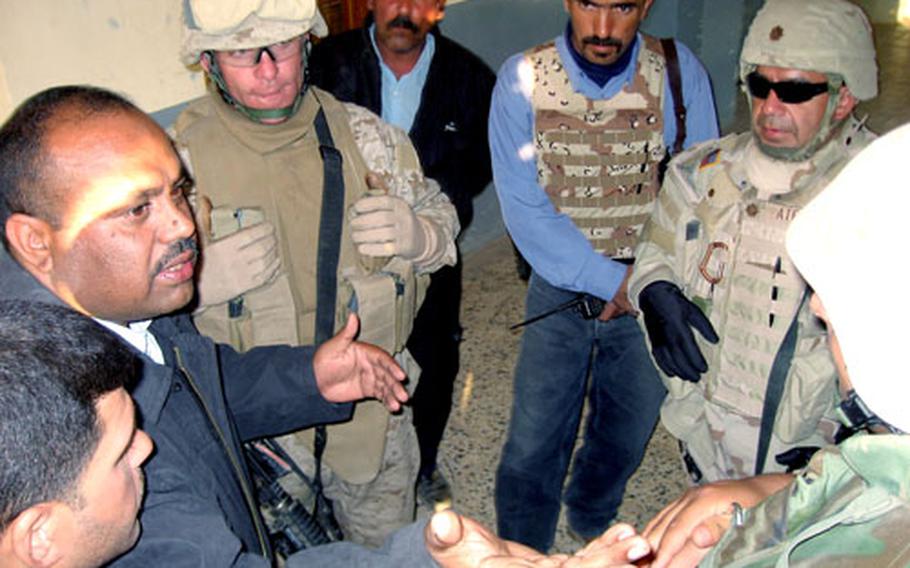Capt. Ghanem Jasim, left, of the Habbaniyah police district in Iraq, speaks to Marine Lt. Col. Bob McCarthy, second from left, and Army Maj. Gregory Atencio, with sunglasses, at the Civil Camp Police Station in Habbaniyah on Friday. McCarthy and Atencio are with Police Transition Team 6, which advises Iraqi police in part of Anbar province. Jasim explained the problems he has experienced with hiring police officers.