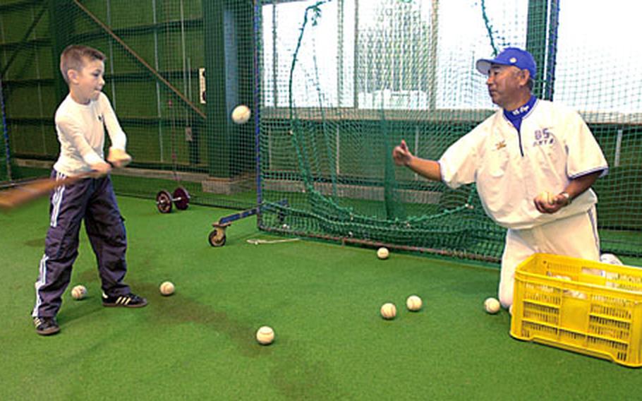 Samuel Kieffer, 8, swings at a toss Saturday from Akihiko Oya, manager for the Japanese baseball team the Yokohama Bay Stars, at Seaside Park in Ginowan City, Okinawa. Samuel said he missed the first few tosses because “I just wasn’t ready to hit.” About a dozen American kids got to meet the manager, coaches and players during one of the team’s practice sessions.