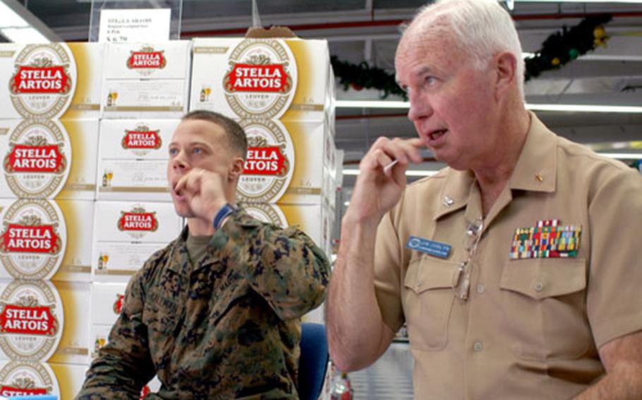 Capt. Jim Joslyn, command chaplain for Naval Station Rota, Spain, and Marine Cpl. Brad Kallman swab their cheeks during registration to become bone marrow donors.