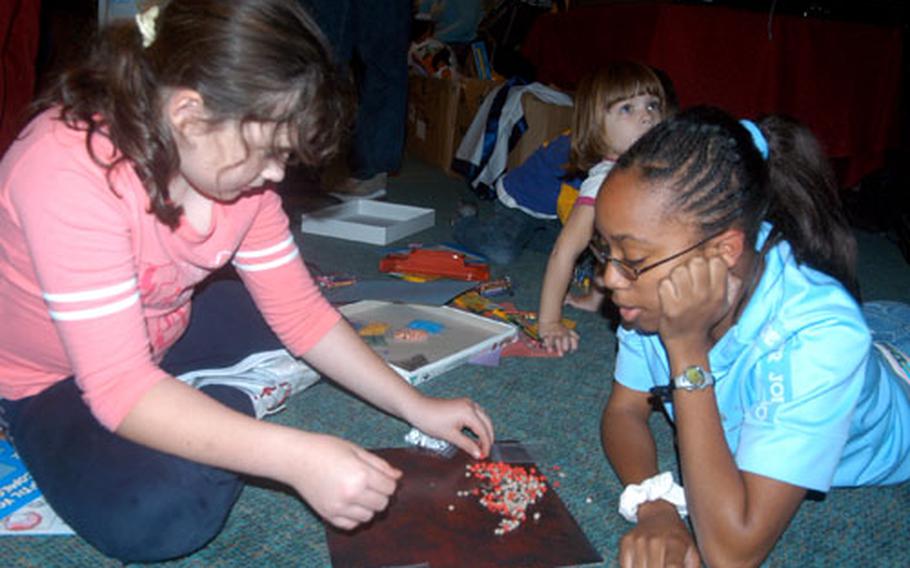 Taylor Bowman, 9, left, and Leanna Kirkland, 15, work with a magnetic-art game during an early Thanksgiving dinner for family members of deployed airmen at RAF Lakenheath last week.