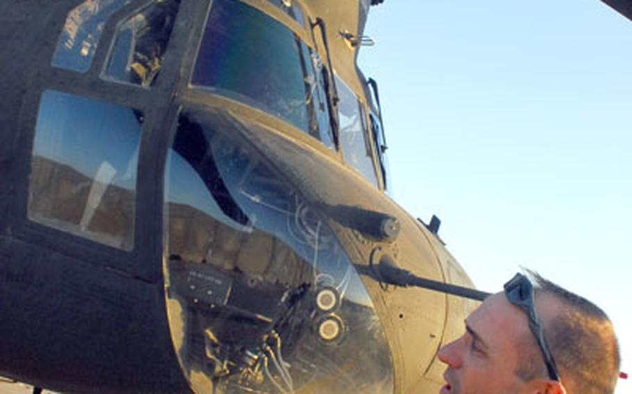 Sgt. 1st Class Geoff Hubbard, a flight engineer and instructor with the Company B "Hill Climbers," 3rd Battalion, 25th Aviation Regiment, looks over a CH-47D Chinook helicopter at Contingency Operating Base Speicher.