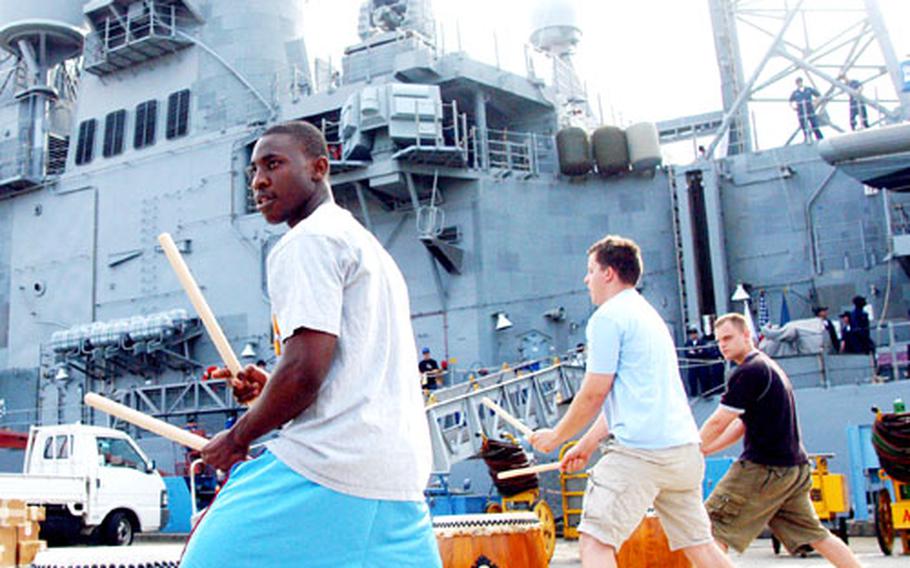Ensign Viktor Lofinmakin, Petty Officer 2nd Class Khris Kiedrowski and Petty Officer 2nd Class Zachary Schmitz practice taiko drumming beside the USS Chancellorsville before the crew swapped to the USS Shiloh at Yokosuka Naval Base, Japan, on Aug. 28.