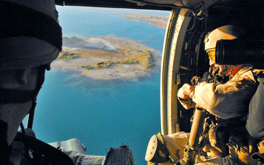The blue waters of Iraq’s Lake Tharthar pass beneath a Black Hawk helicopter and a Navy bomb disposal team during a recent “Lightning Strike” mission in northern Iraq.