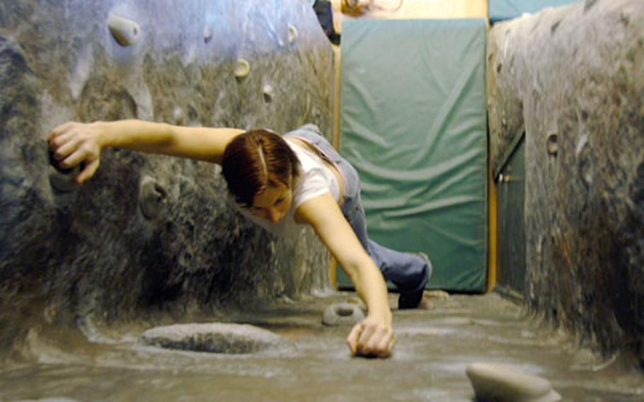 Anya Clark inches her way upward on a series of handholds in a corner of the rock gym. Nestled among the various other gyms, aerobics rooms and game tables at the center, the climbing wall comprises a mixed bag of pros and cons for would-be climbers.