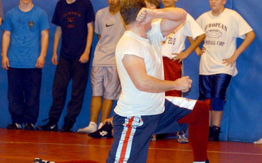 Airman 1st Class Roy Phillips, foreground, a volunteer coach for the Lakenheath Lancers, goes over a wrestling move during a recent practice.