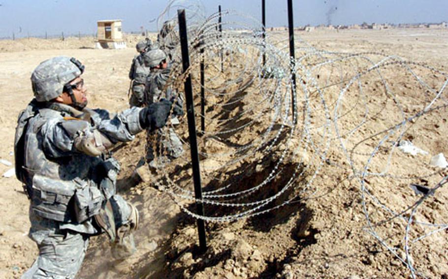 Pfc. Arturo Vargas of San Diego and his unit mates from the 9th Engineer Battalion install concertina wire atop a berm that surrounds the Iraqi police station in Zangora, Iraq, a town near Ramadi.