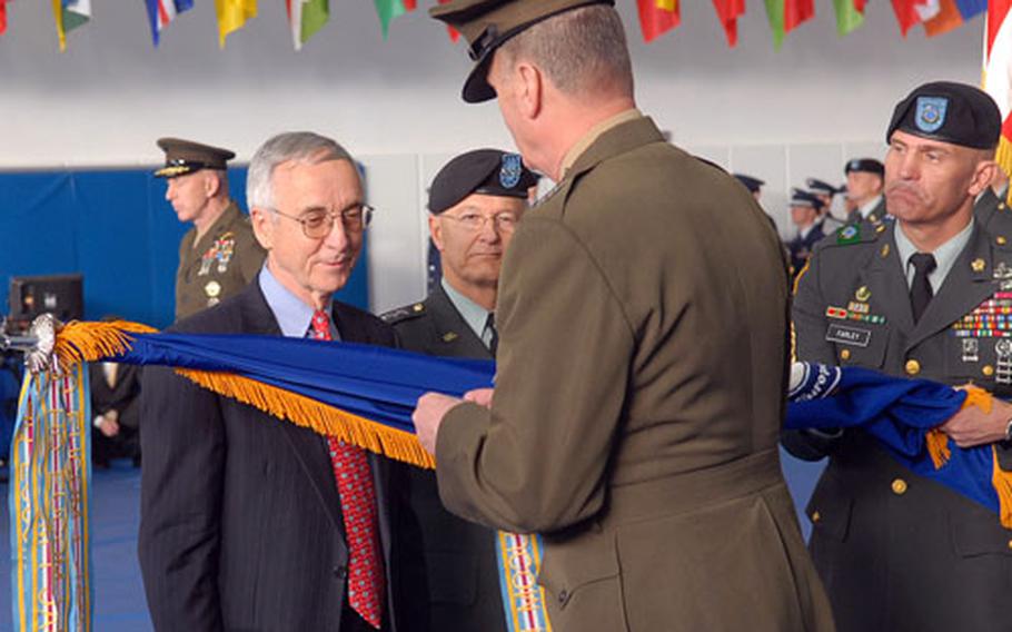 Deputy Secretary of Defense Gordon England, left, and Gen. Bantz J. Craddock watch as Marine Gen. James L. Jones adds an award to the U.S. European Command colors during the change-of-command ceremony at Patch Barracks in Stuttgart-Vaihingen, Germany, on Monday.
